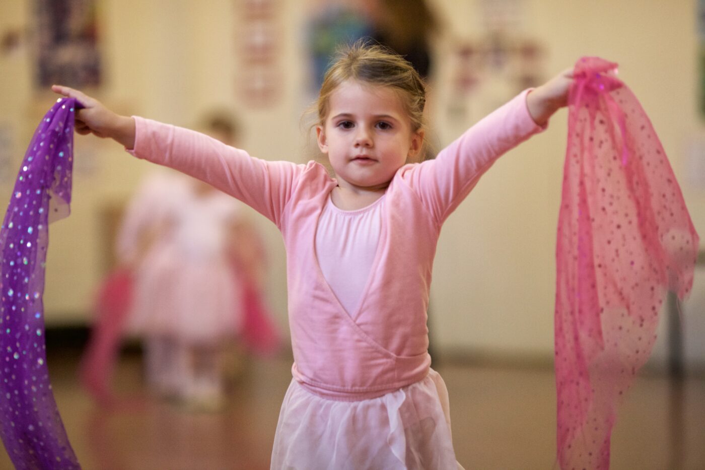 nursery ballet girl holding scarves for a dance, in her pink uniform